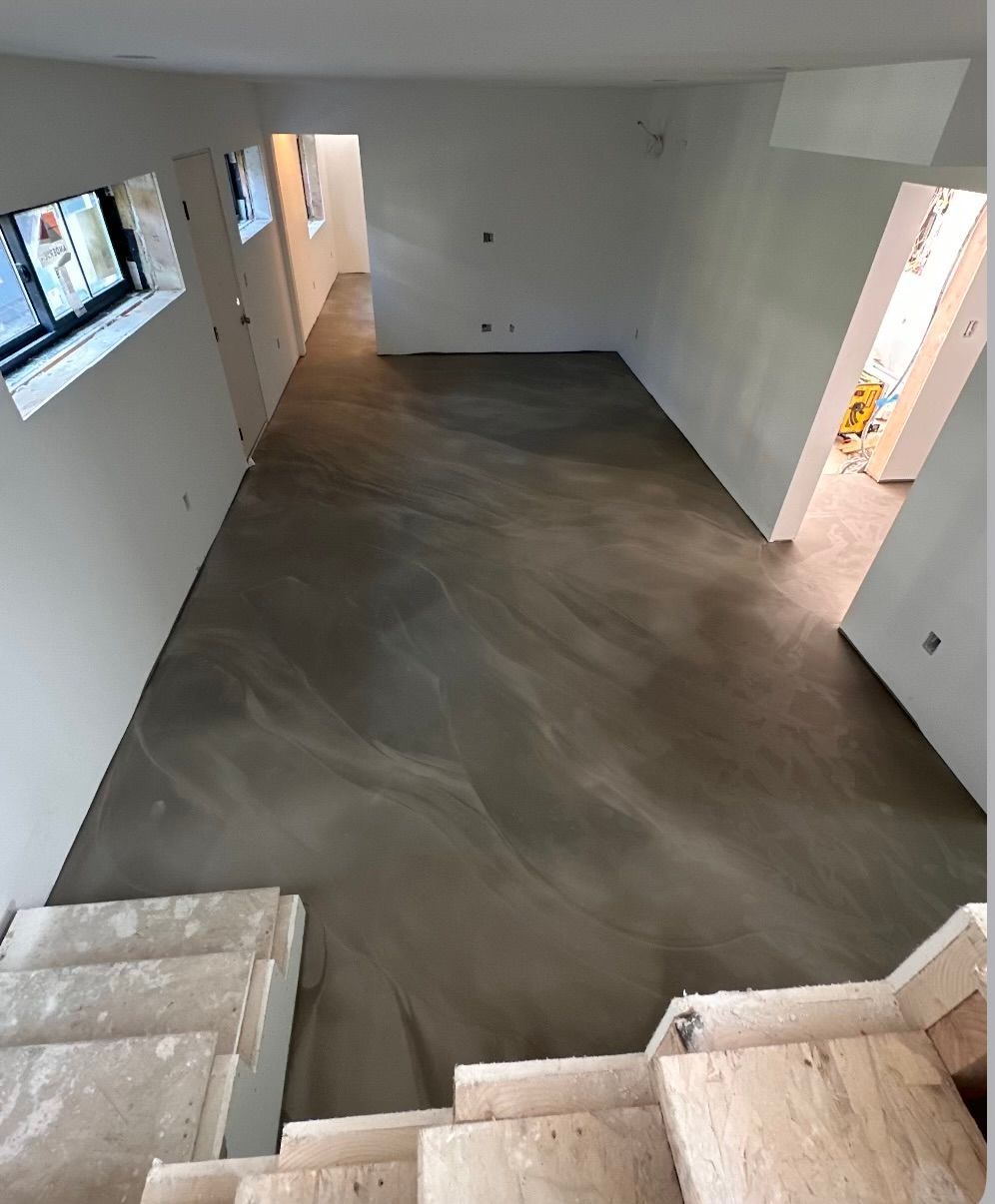 A room with a concrete floor and stairs leading up to it.