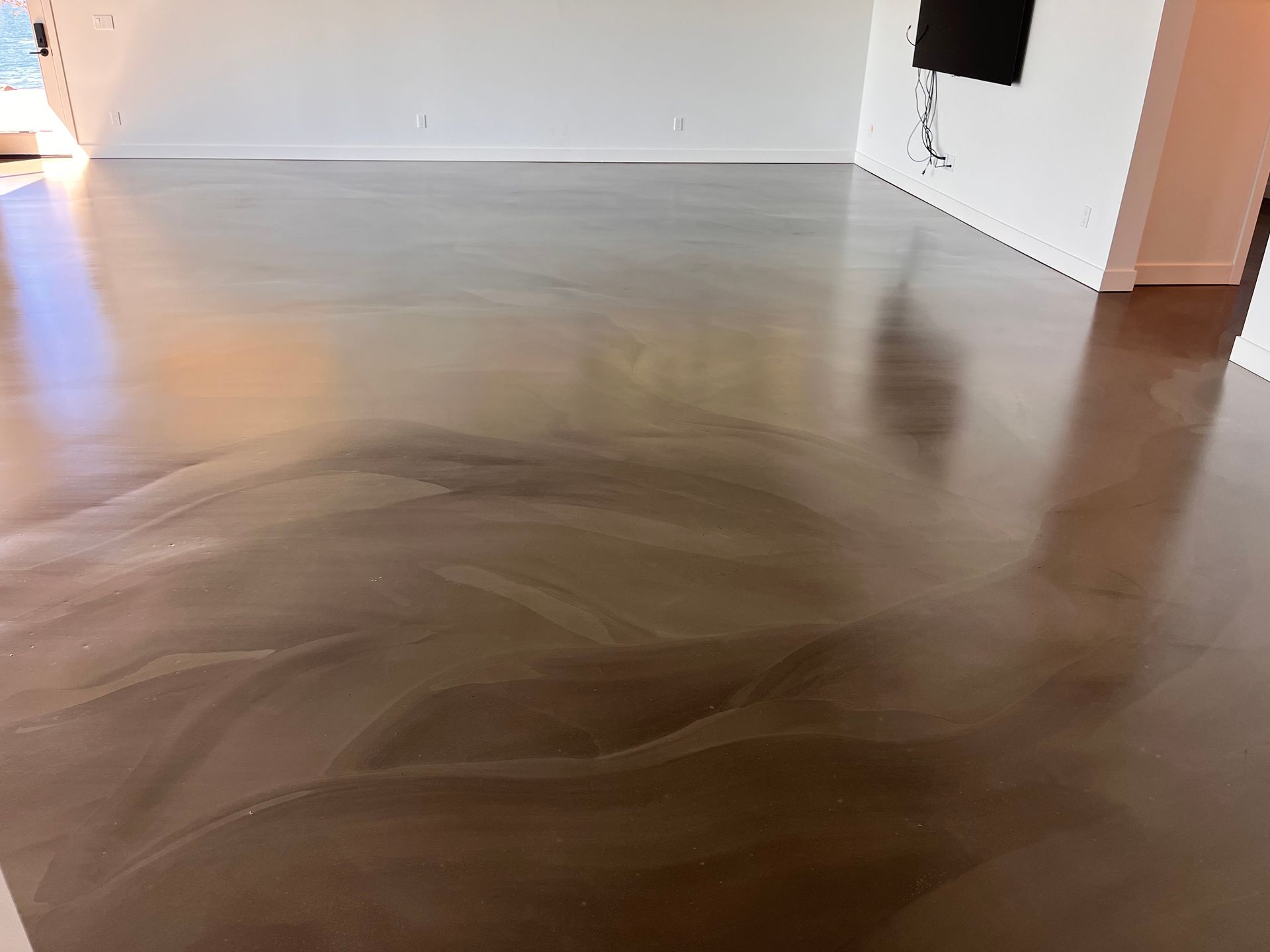 A living room with a shiny concrete floor and a white wall.
