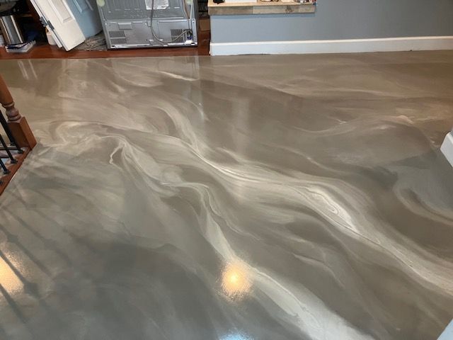A silver metallic floor in a living room with a staircase in the background.