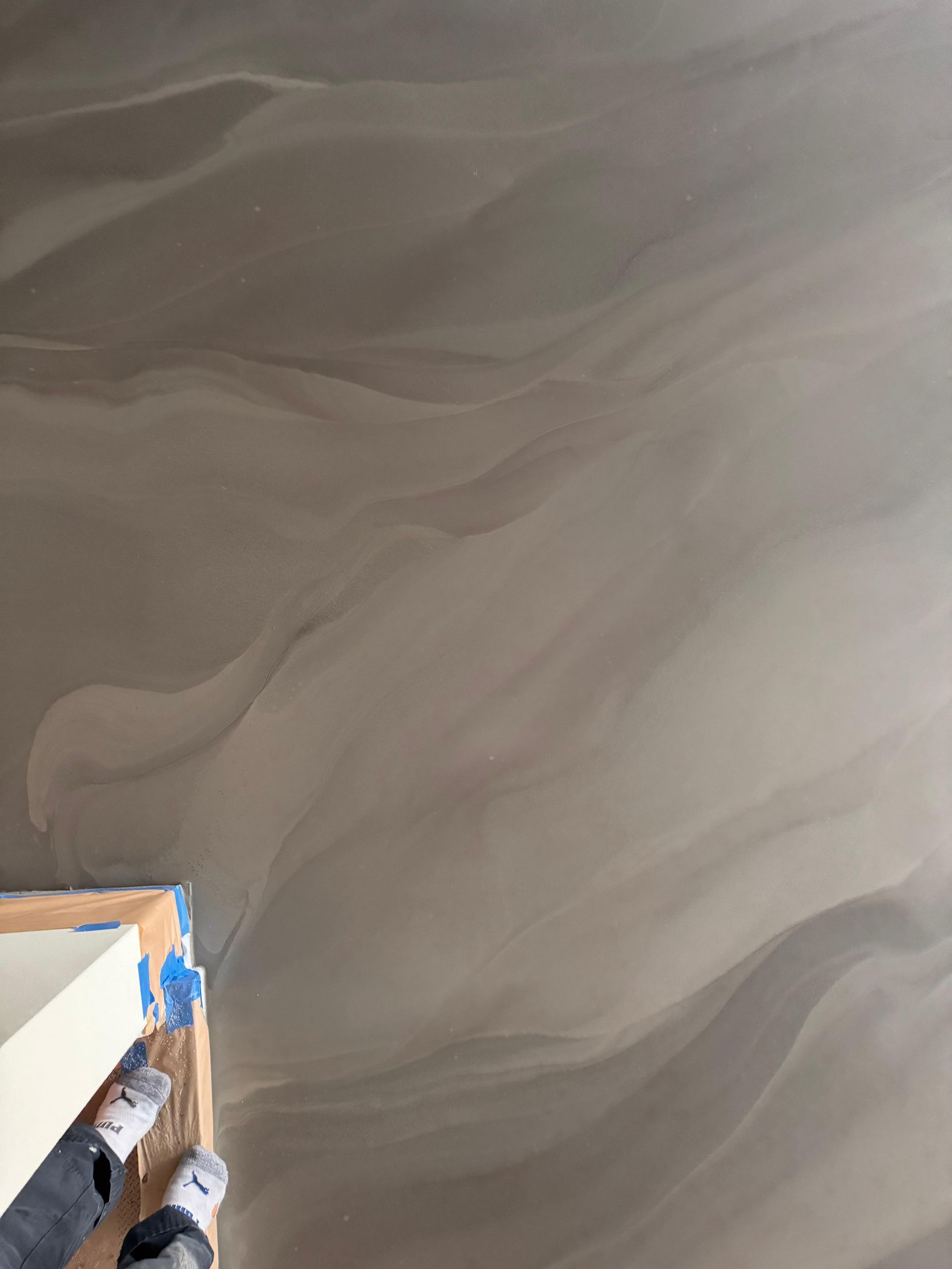 A person is standing on a concrete floor next to a box.