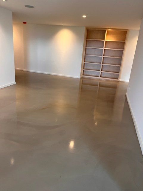 A large empty room with a concrete floor and shelves.