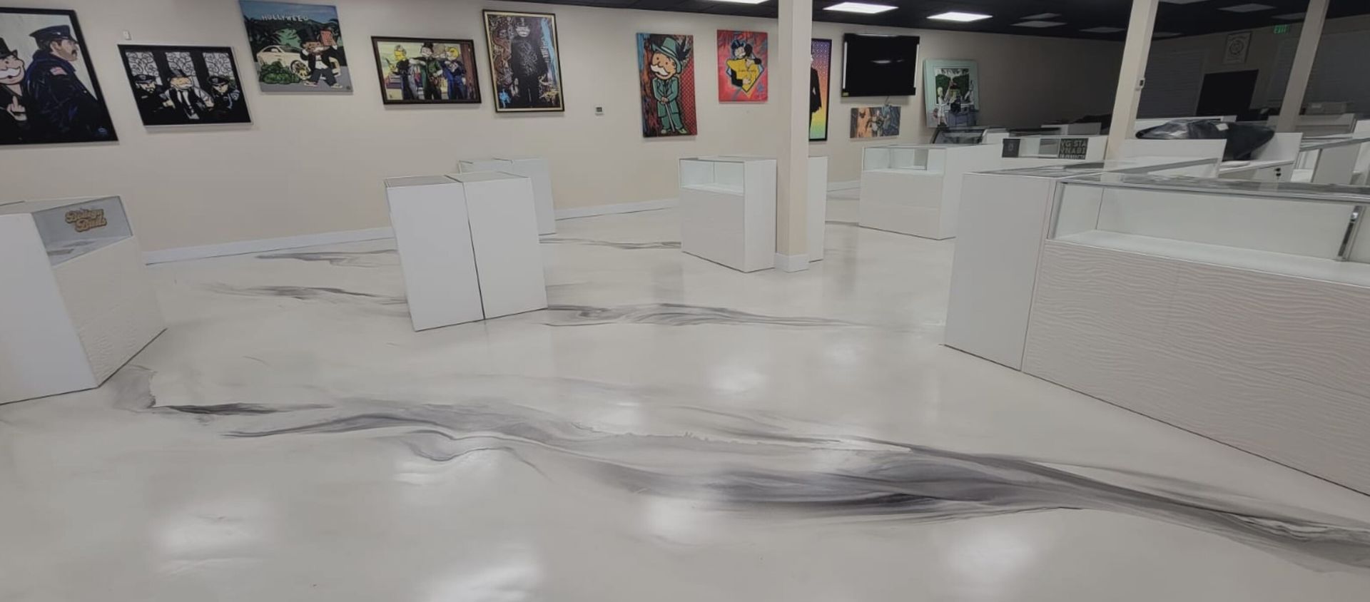 A room with a lot of paintings on the walls and a white floor.