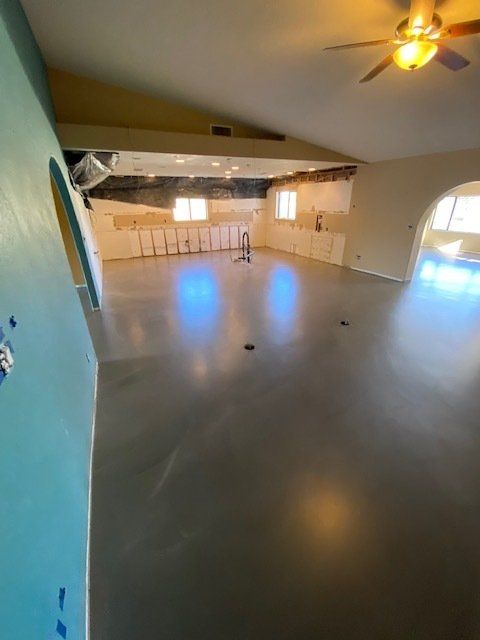 A large room with a ceiling fan and a ladder.