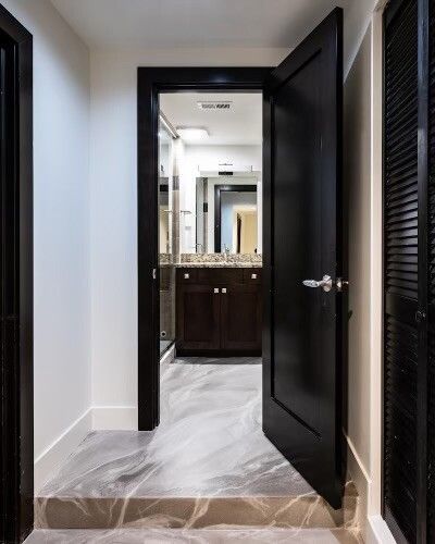 A hallway with a black door leading to a bathroom.