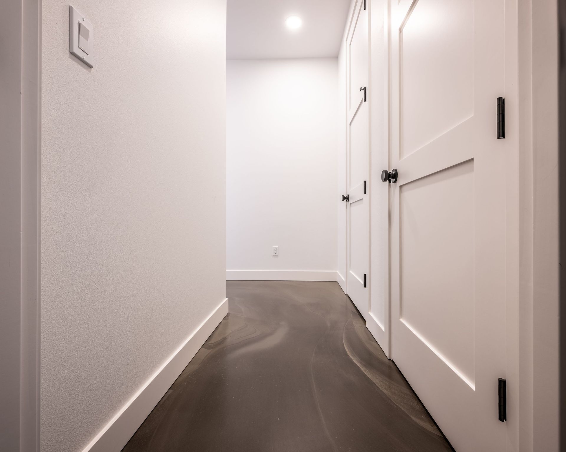 A hallway with white doors and a dark floor