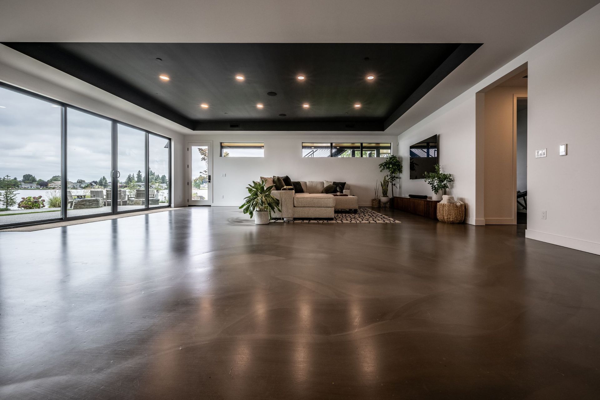 A living room with a couch , television , and large windows.