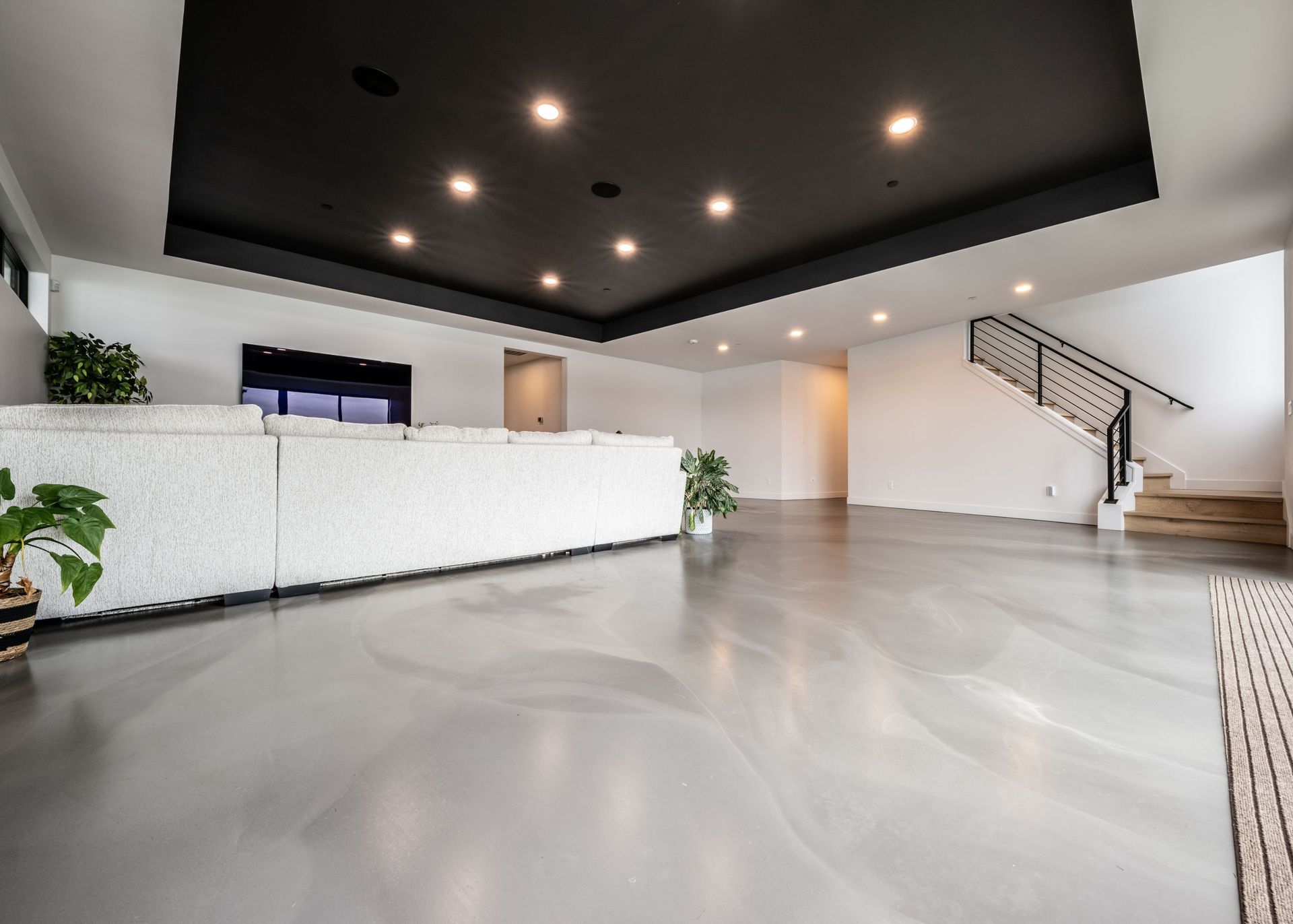 A living room with a couch , stairs and a black ceiling.
