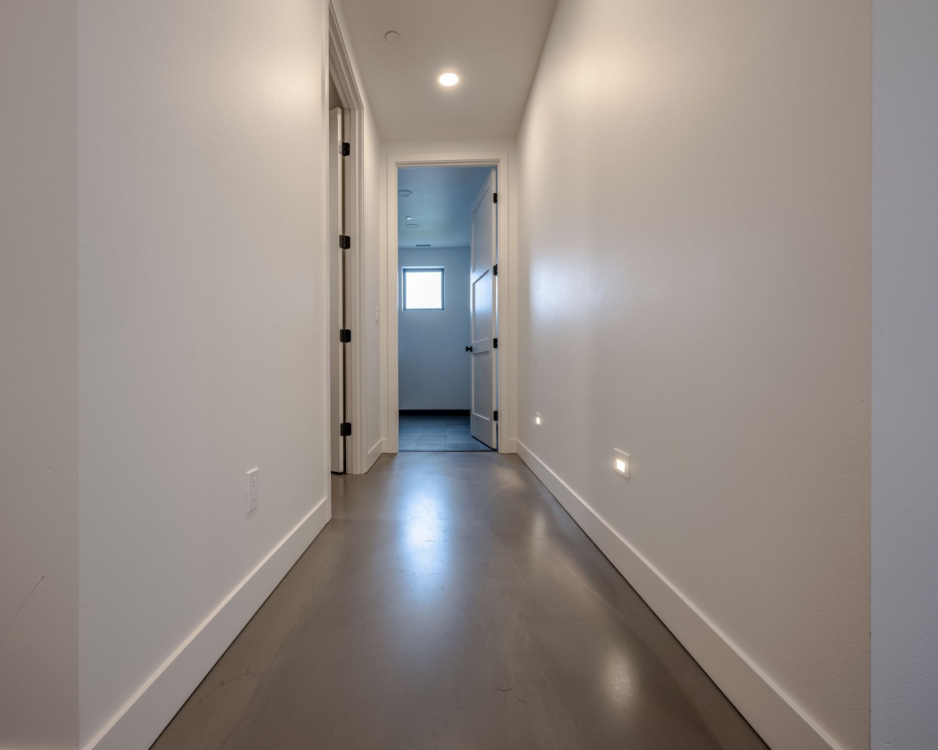 A hallway with white walls and a gray floor