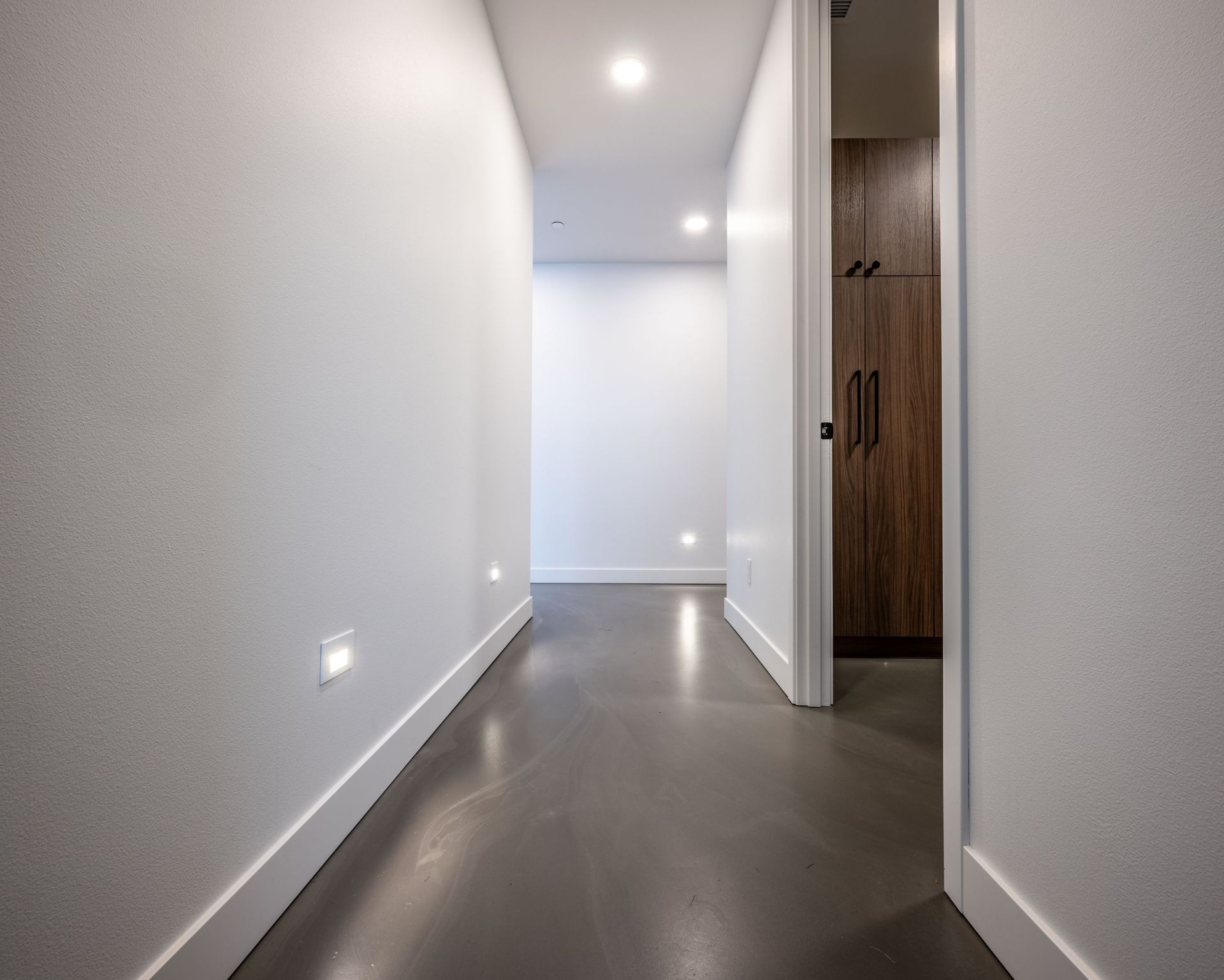 A long hallway with a gray floor and white walls