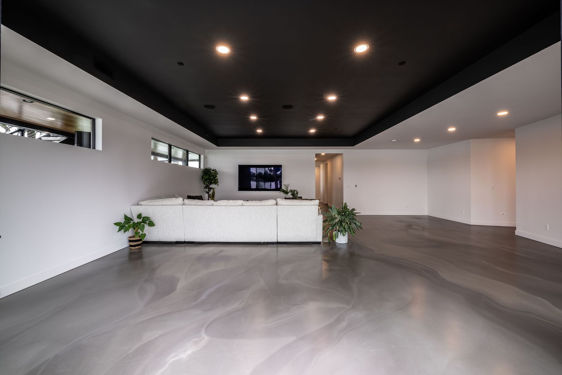 A large empty room with a black ceiling and a white couch.
