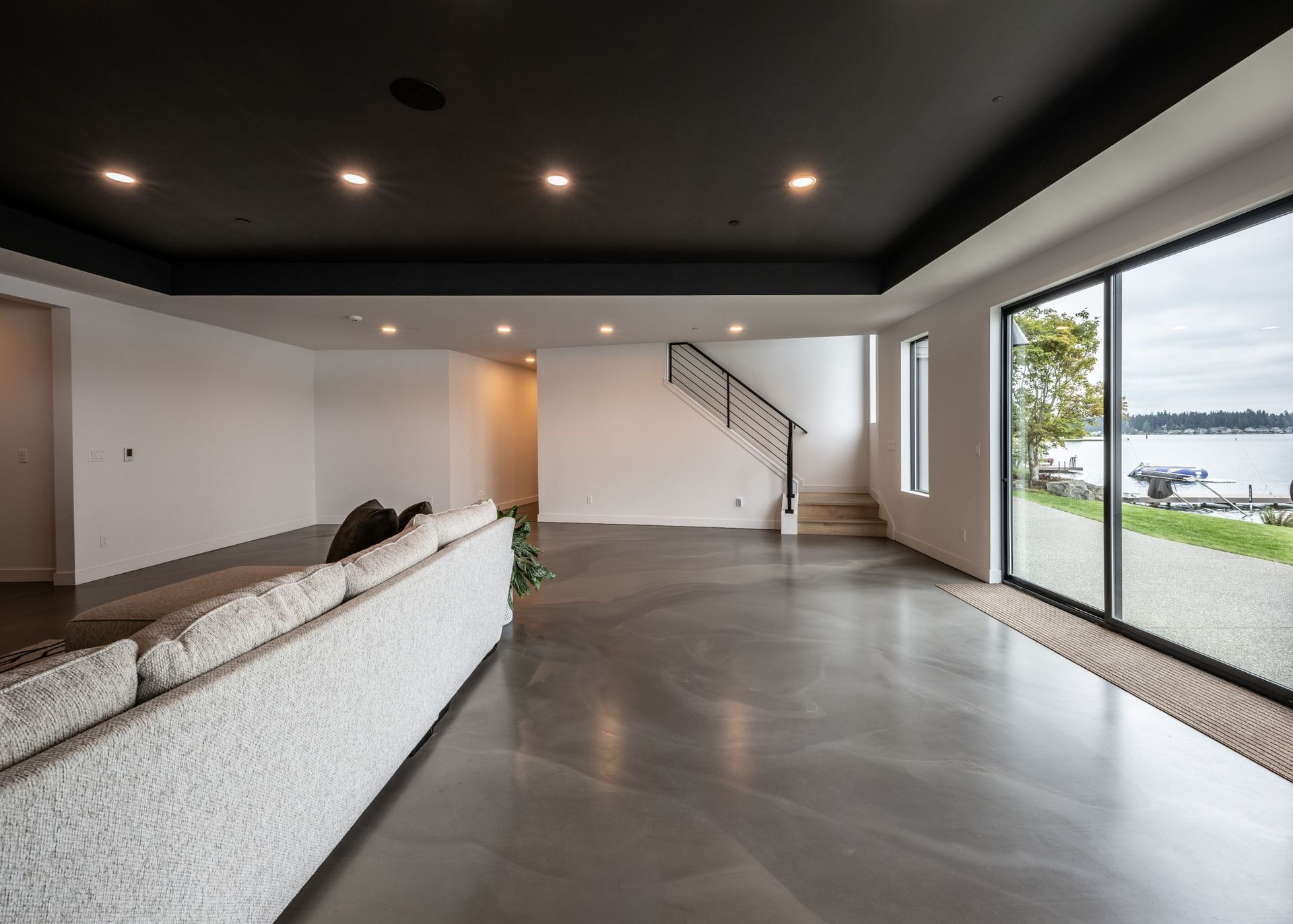 A living room with a couch , stairs and a view of a lake.