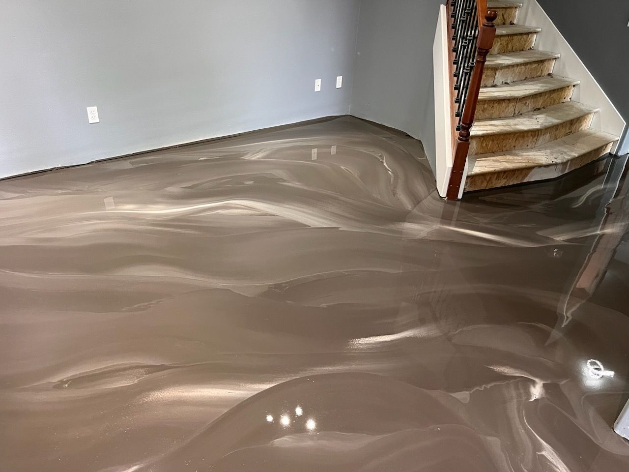 A room with a shiny floor and stairs in the background.