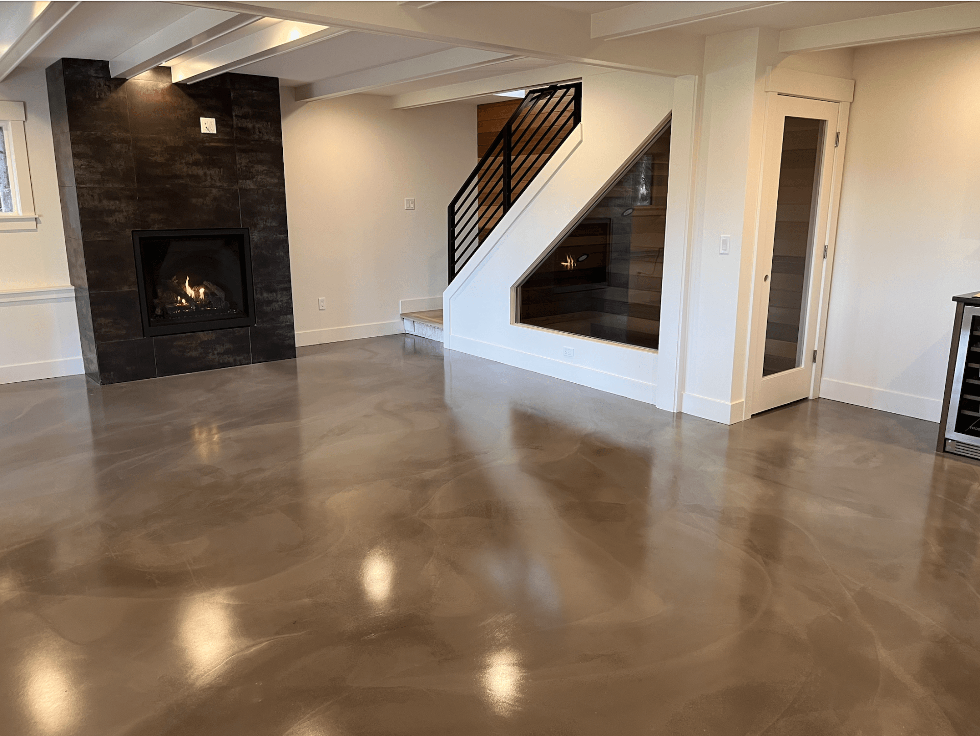 A living room with a fireplace , stairs and a concrete floor.