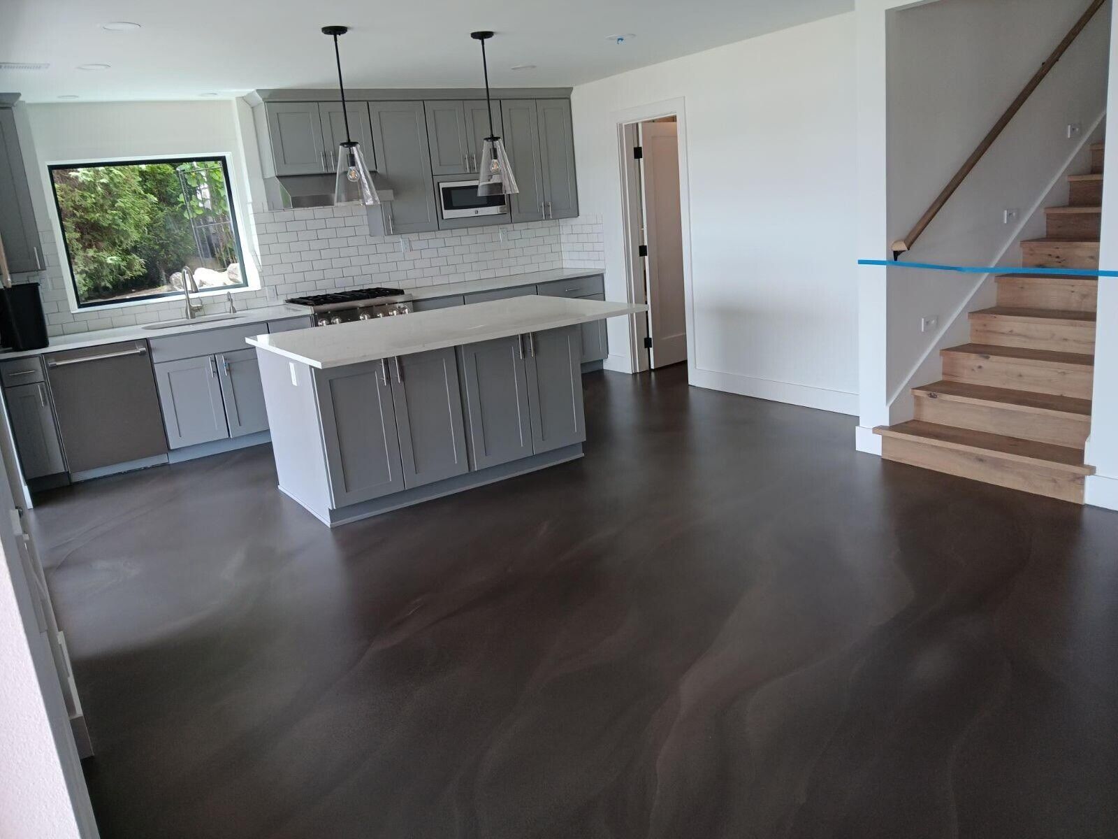 A kitchen with a large island and stairs in the background.