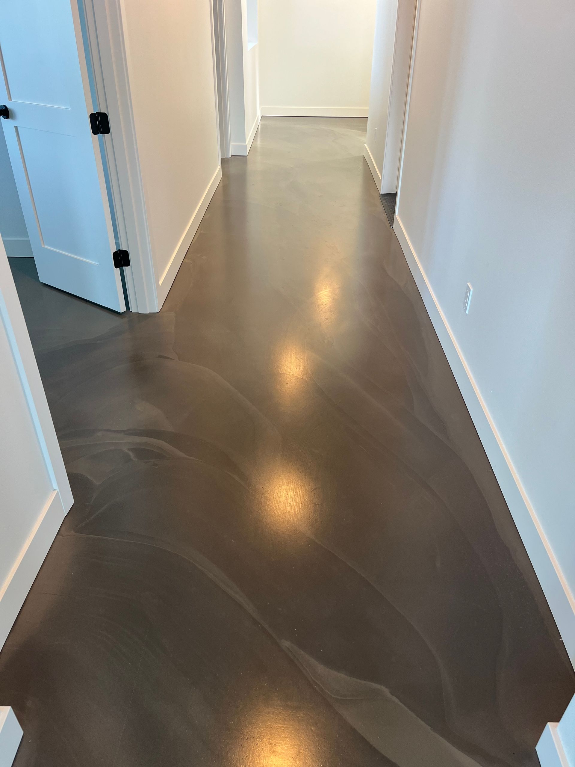 A hallway with a concrete floor and white walls.