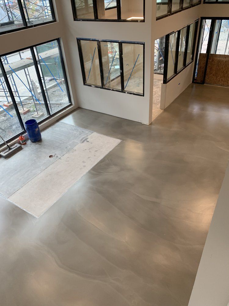 A large room with a concrete floor and lots of windows.