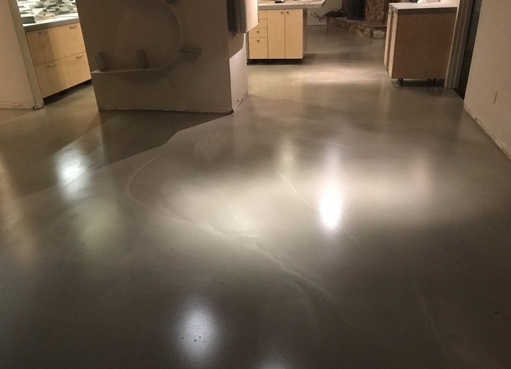 A kitchen with a shiny concrete floor and cabinets.