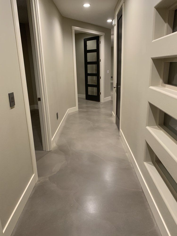 A hallway in a house with a concrete floor and stairs.