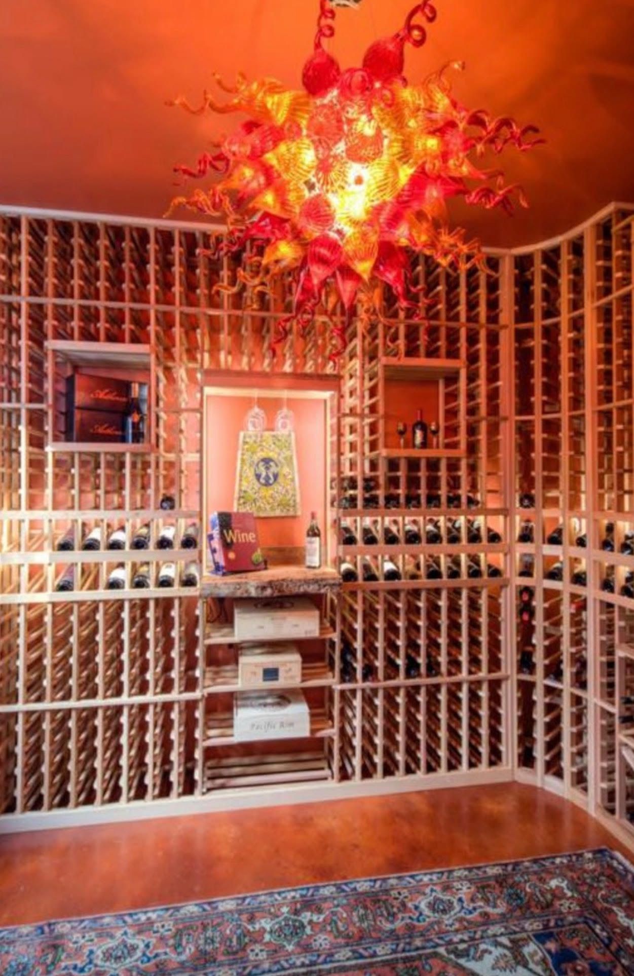 A wine cellar filled with lots of wine bottles and a chandelier hanging from the ceiling.