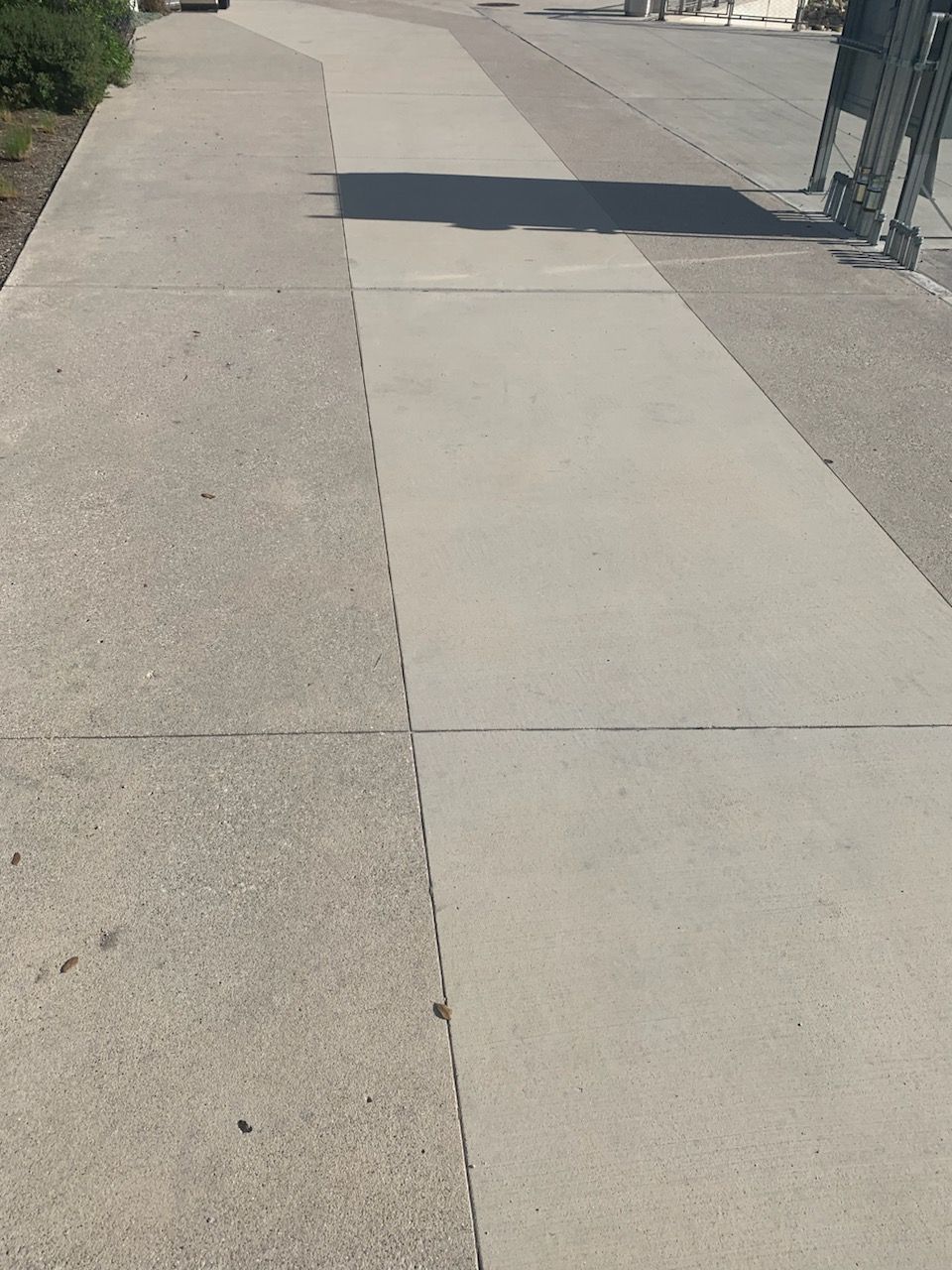 A concrete sidewalk with a shadow on it