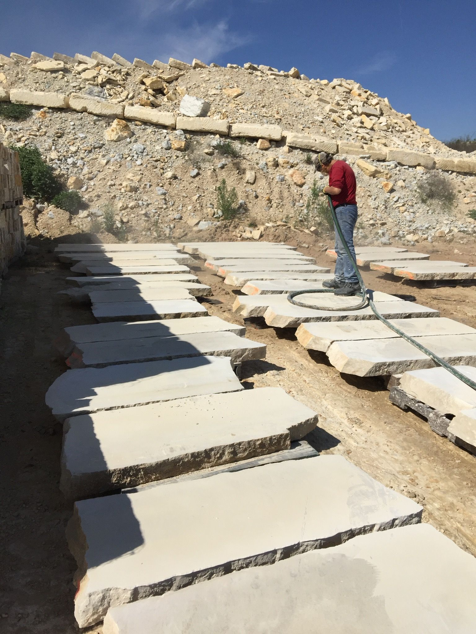 A man in a red shirt is standing on a row of concrete slabs.