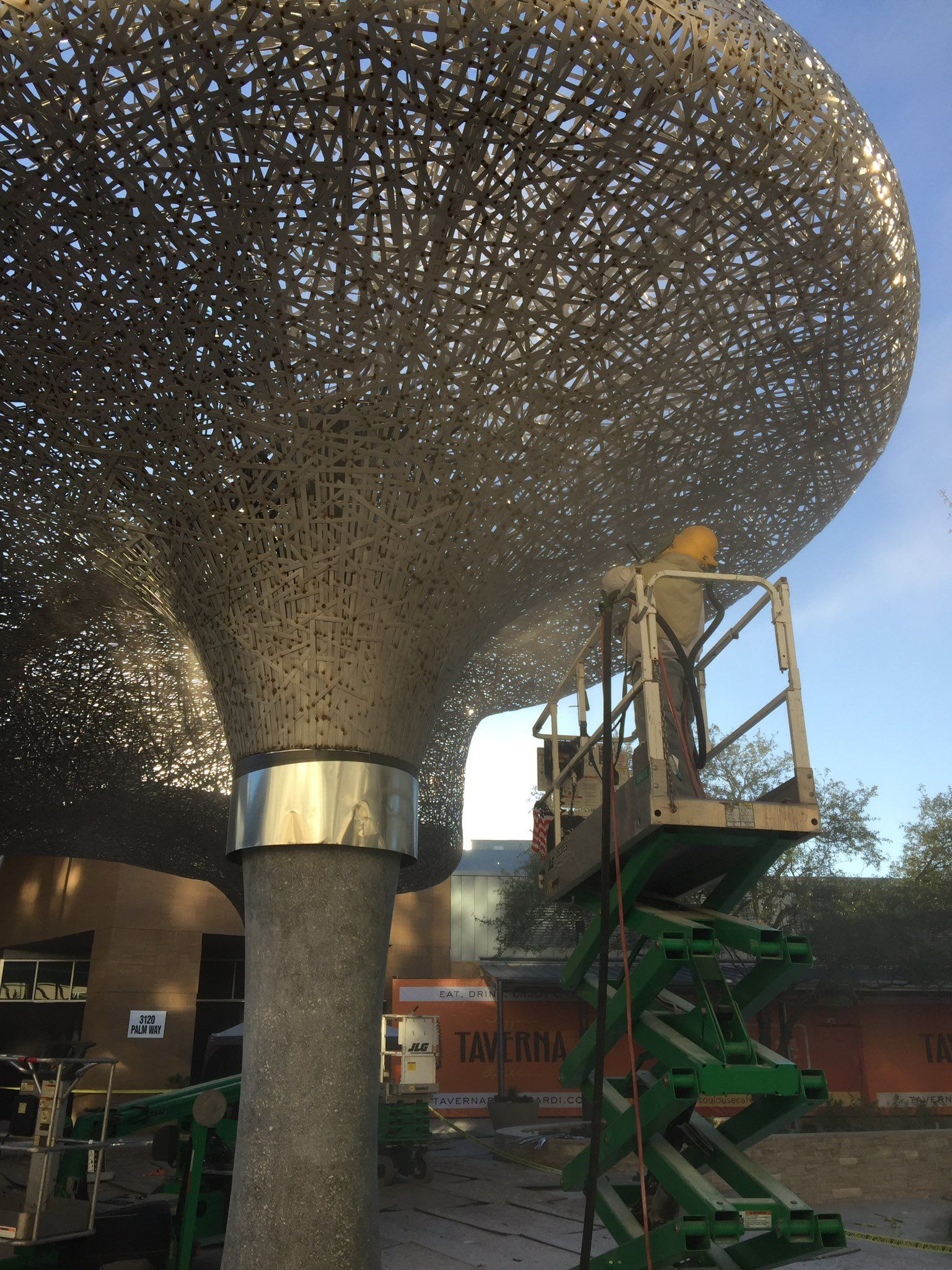 A man is standing on a lift working on a sculpture