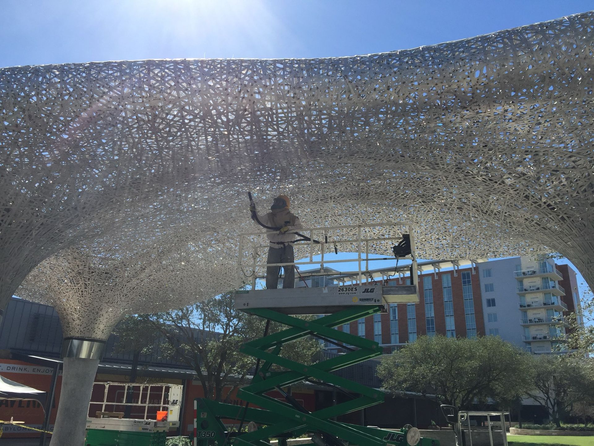 A man is standing on a scissor lift working on a sculpture.