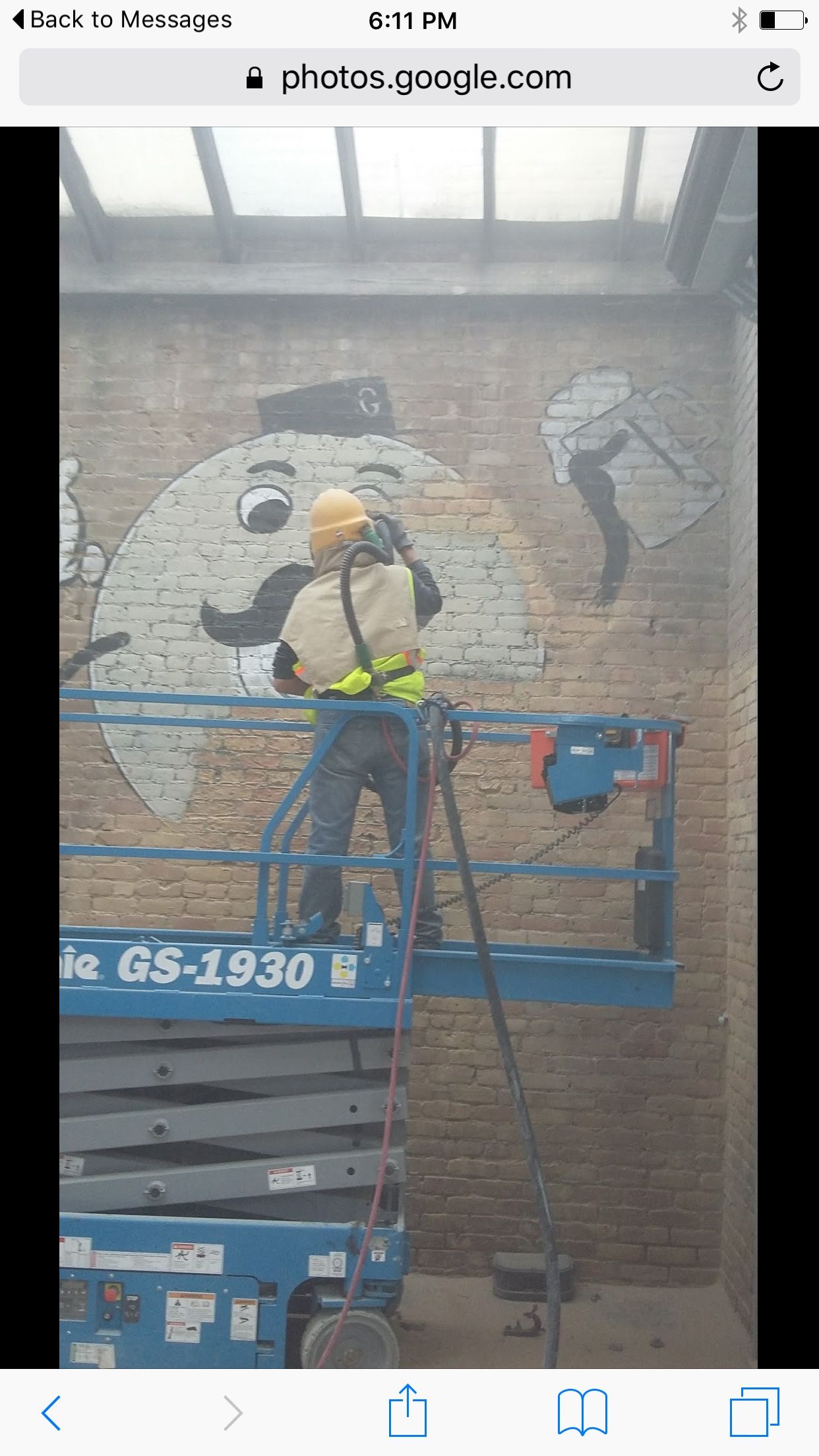 A man is cleaning a brick wall with a machine.