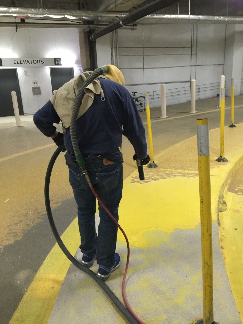 A man in a blue shirt is using a vacuum cleaner on a yellow surface