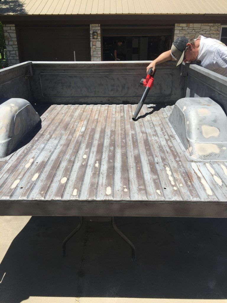 A man is cleaning the back of a truck with a vacuum cleaner.