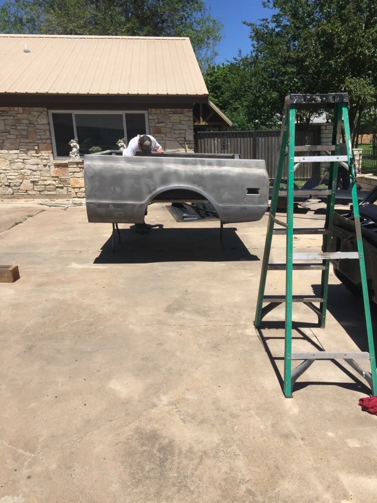 A truck bed is sitting in a driveway next to a ladder.