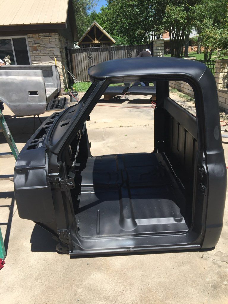 A black truck cab is sitting on the ground in front of a house.