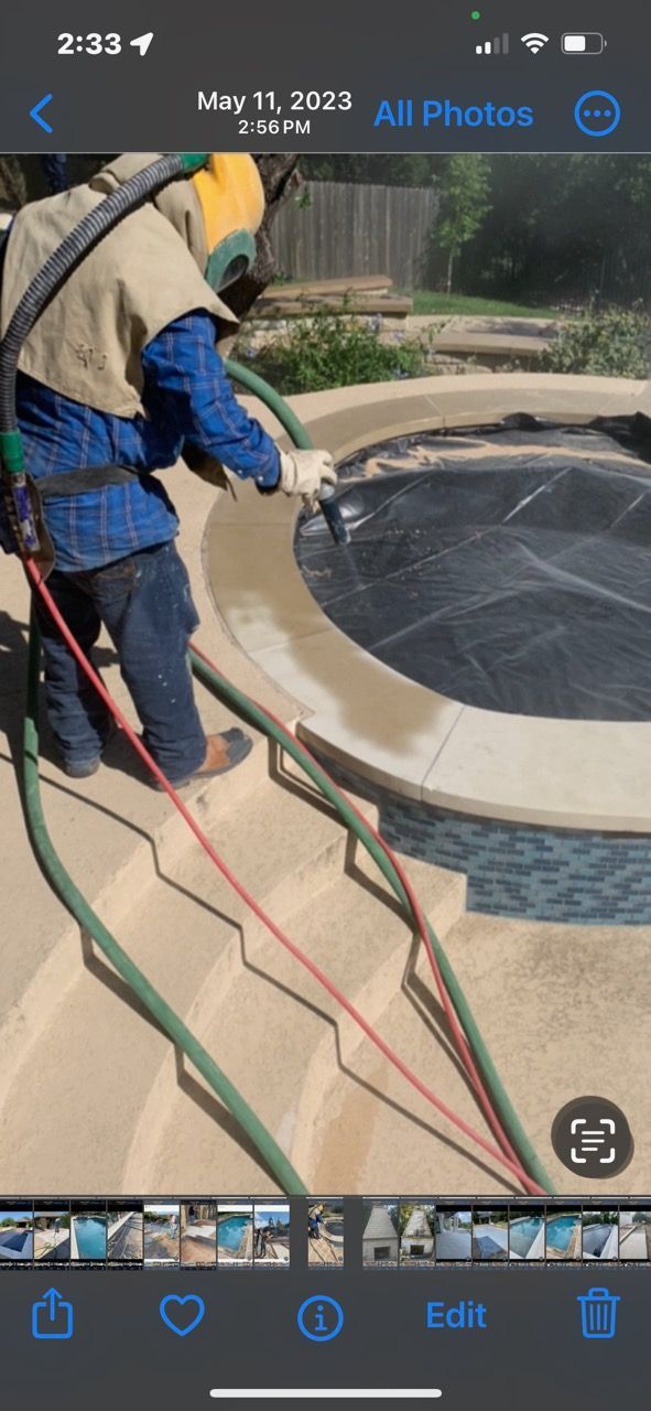 A man is sandblasting a pool with a hose.