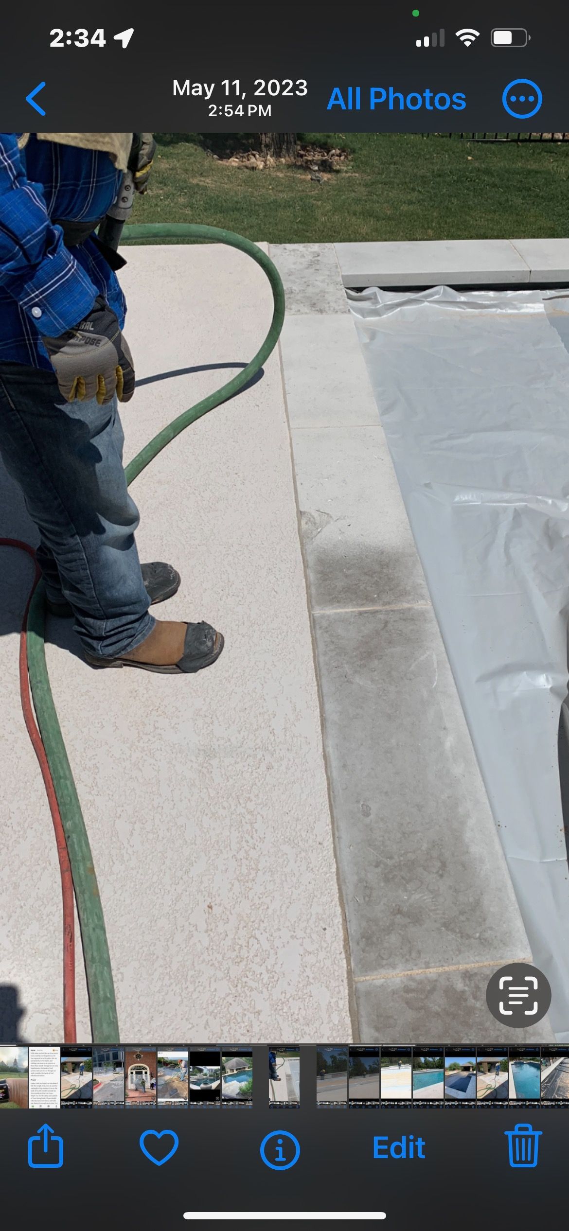 A person is standing next to a hose on a sidewalk.