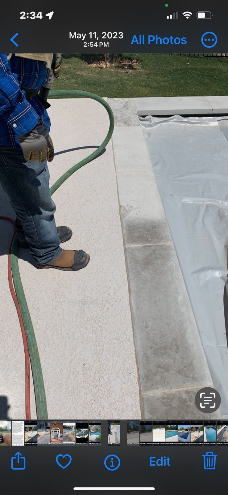 A person is standing next to a hose on a sidewalk.