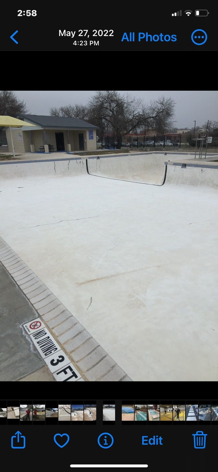A phone screen shows a picture of a swimming pool being built.