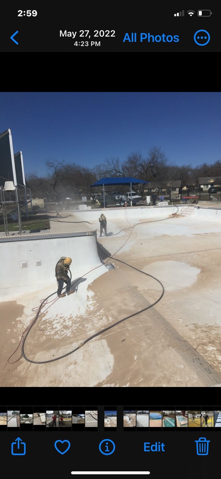 A man is using a hose to clean a pool.