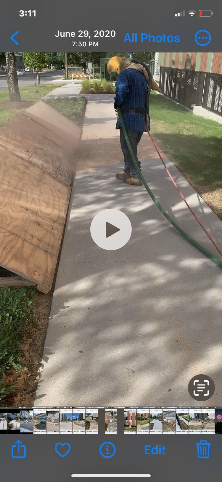 A man is cleaning a sidewalk with a hose.