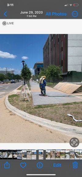 A person is riding a skateboard on a sidewalk in front of a building.