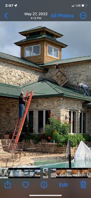 A man is standing on a ladder on the roof of a building.