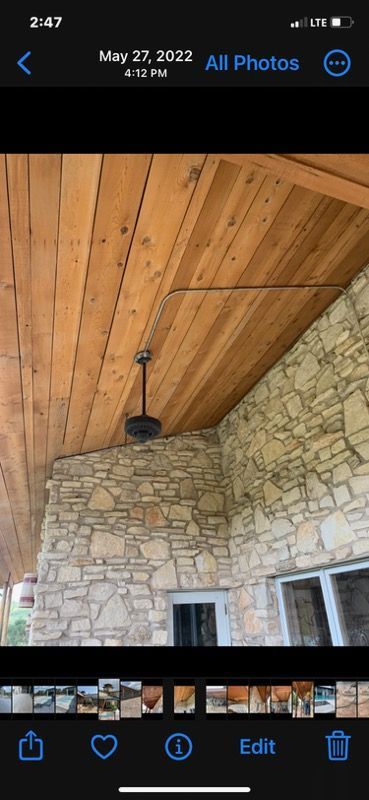 A ceiling fan is hanging from the ceiling of a stone building.