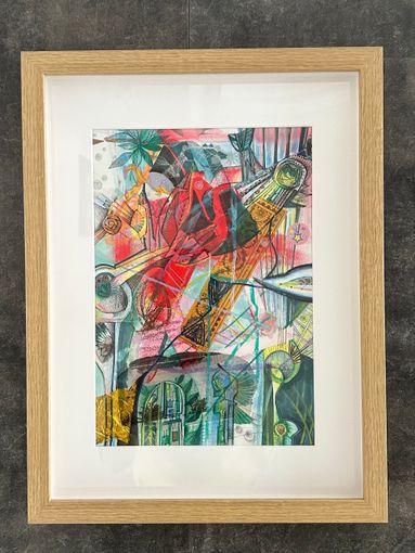 Abstract, kleurrijk schilderij in een licht houten frame met een witte passe-partout tegen een grijze muur.