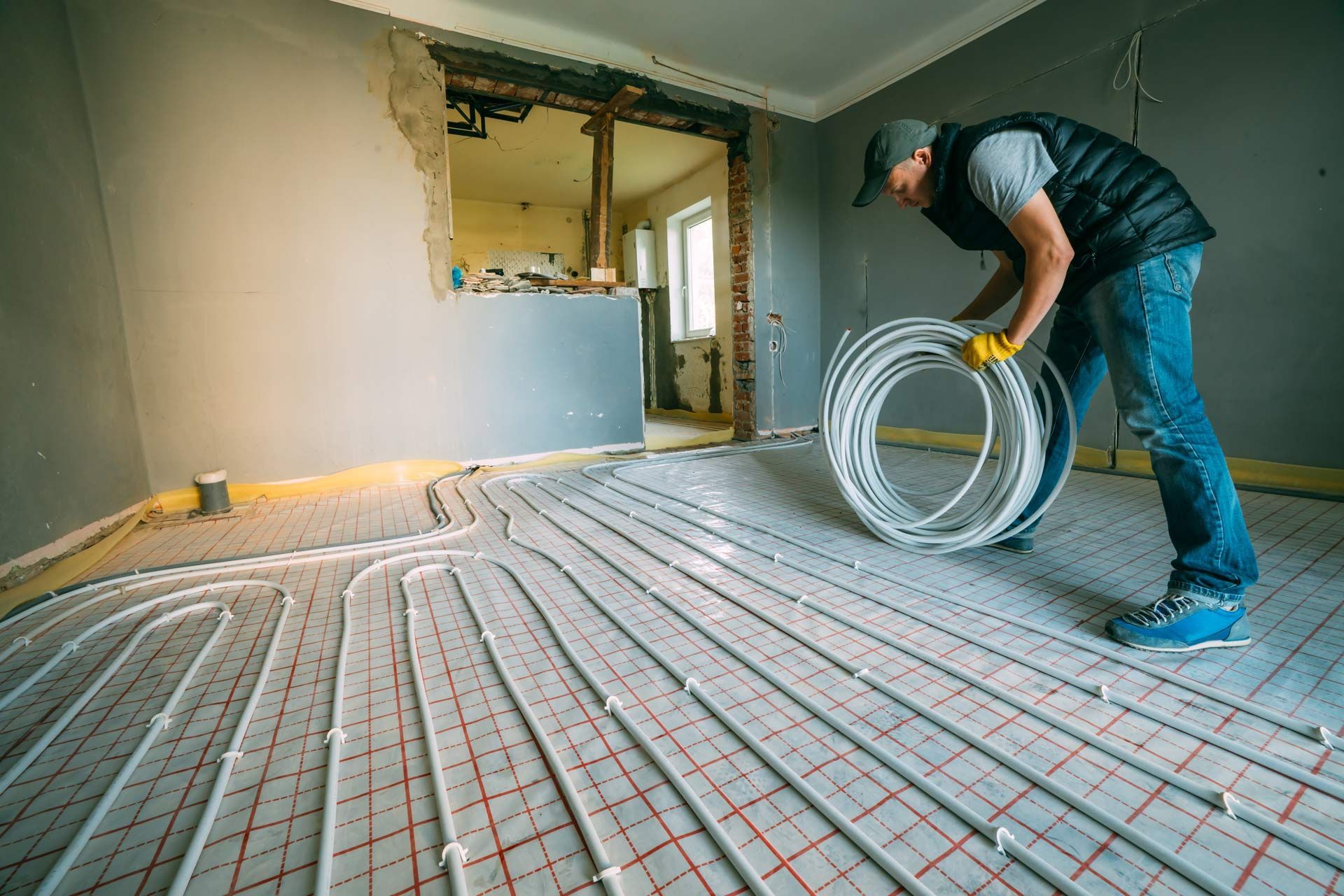A man is rolling a roll of pipe on a floor.