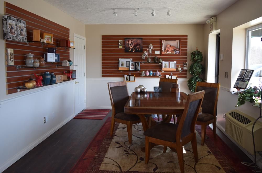 a room with a table and chairs in front of a wall with pictures on it