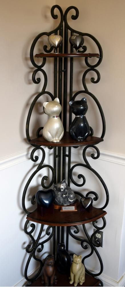 a wrought iron shelf with cat urns and hearts urns on it