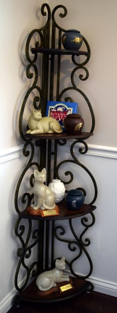 a wrought iron corner shelf with a cat urns