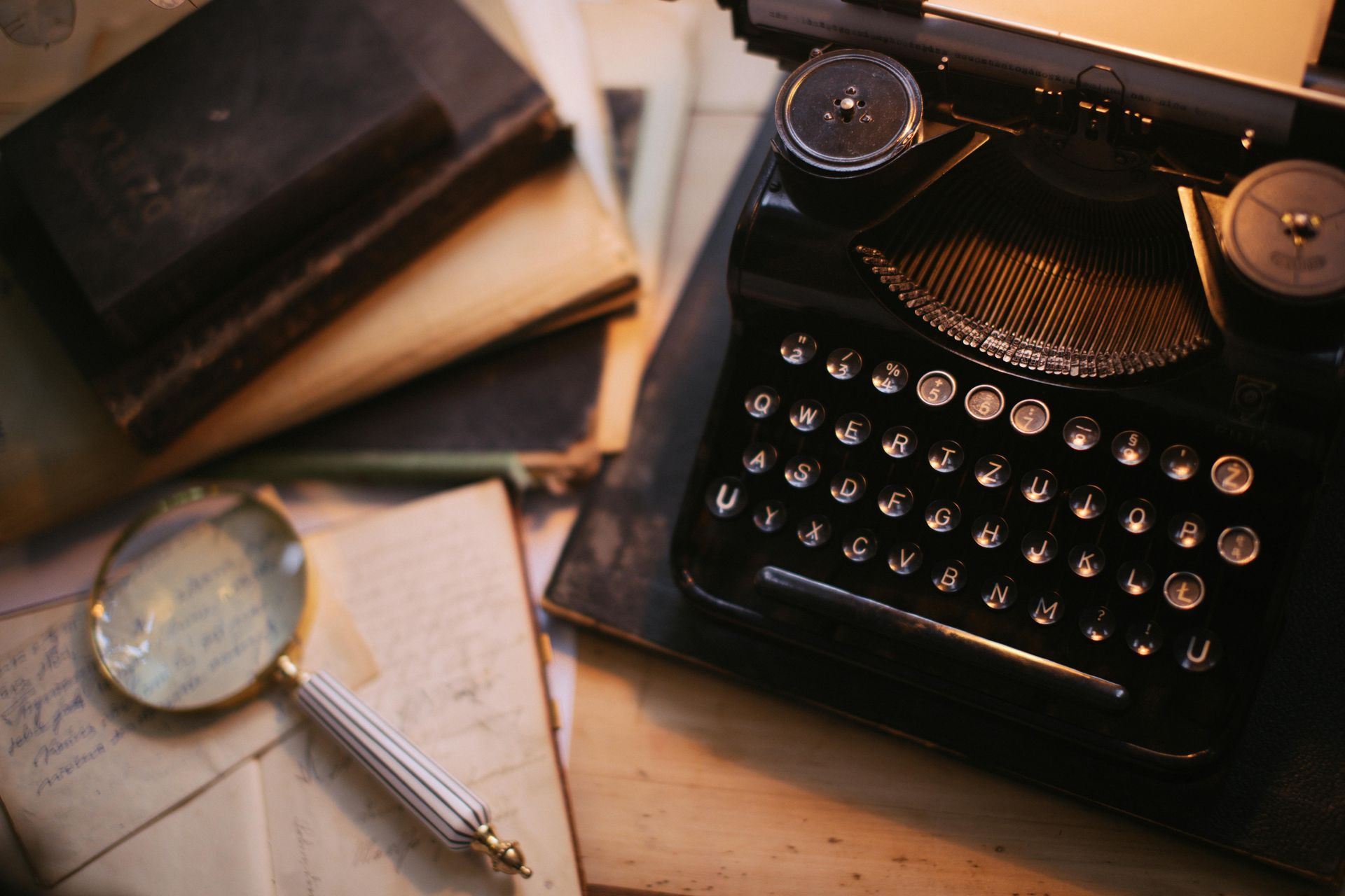 Vintage typewriter, books, magnifying glass, papers; a writer's workspace with a historical feel.
