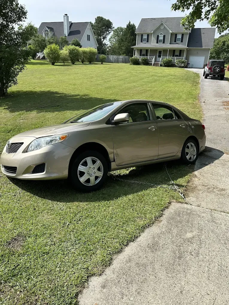 A car is parked on the side of the road in front of a house.