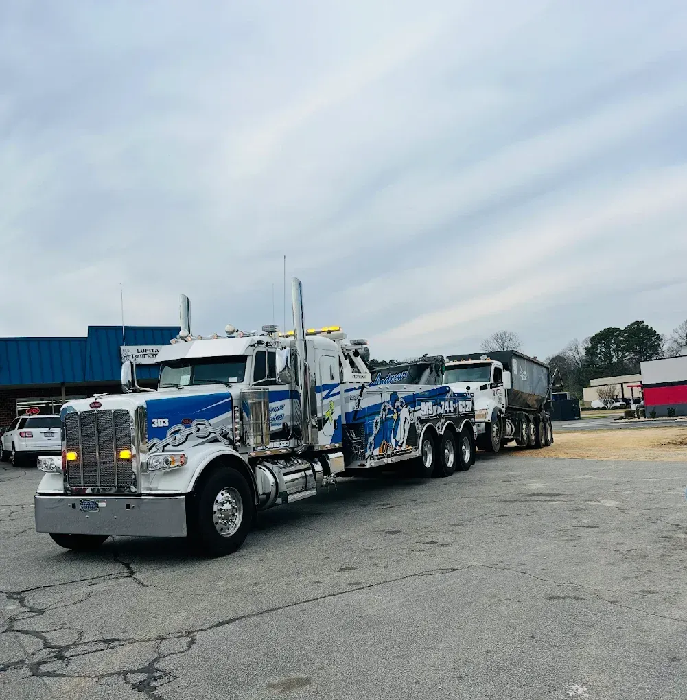 A blue and white tow truck is parked in a parking lot.