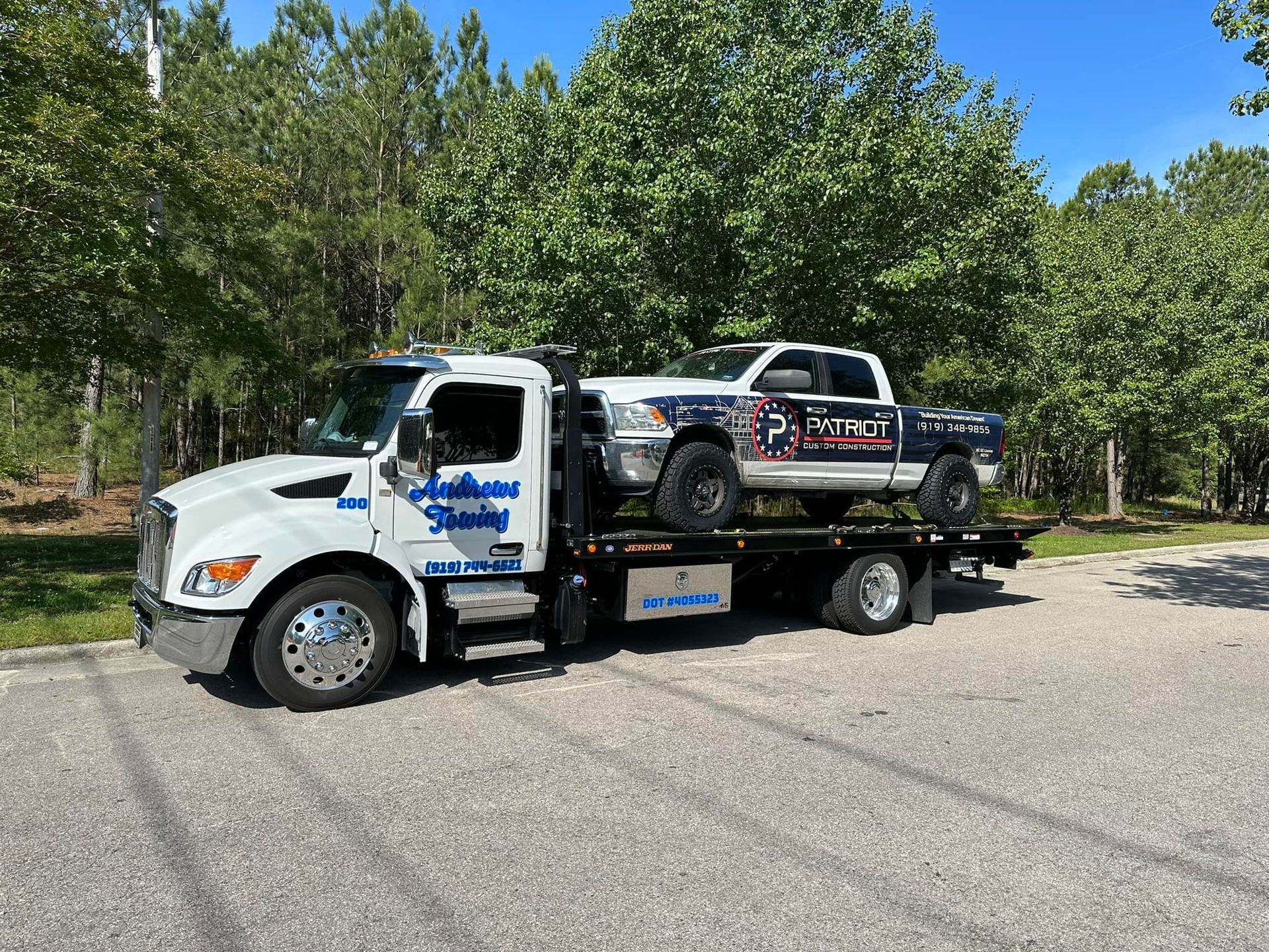 A tow truck is carrying a truck on the back of it.